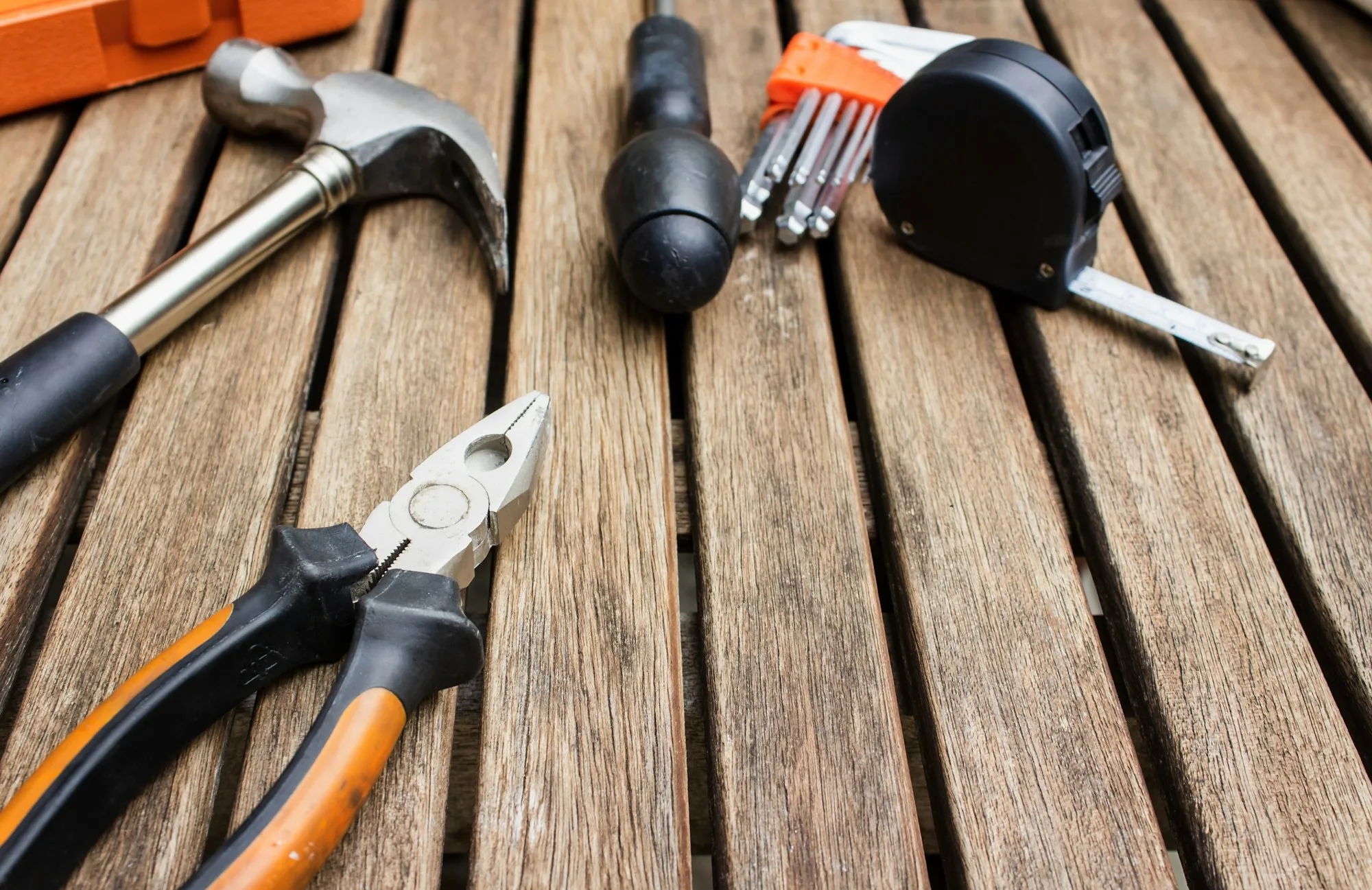 Pliers, hammer and tape measure on wooden boards